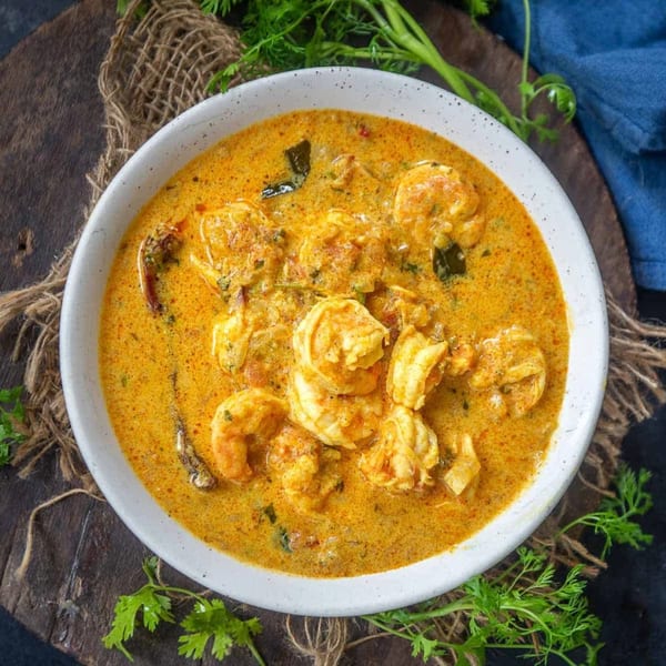 Overhead view of a white bowl filled with Papa's India Grill's creamy shrimp curry, garnished with fresh cilantro.